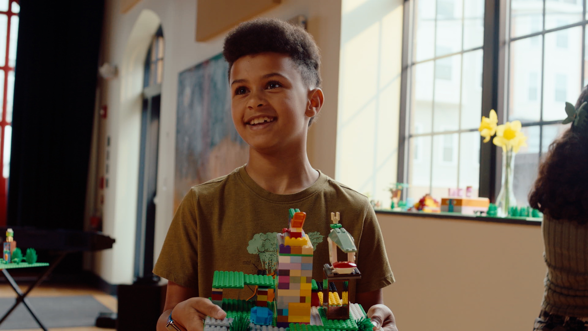 A young creator presenting his colorful LEGO brick build