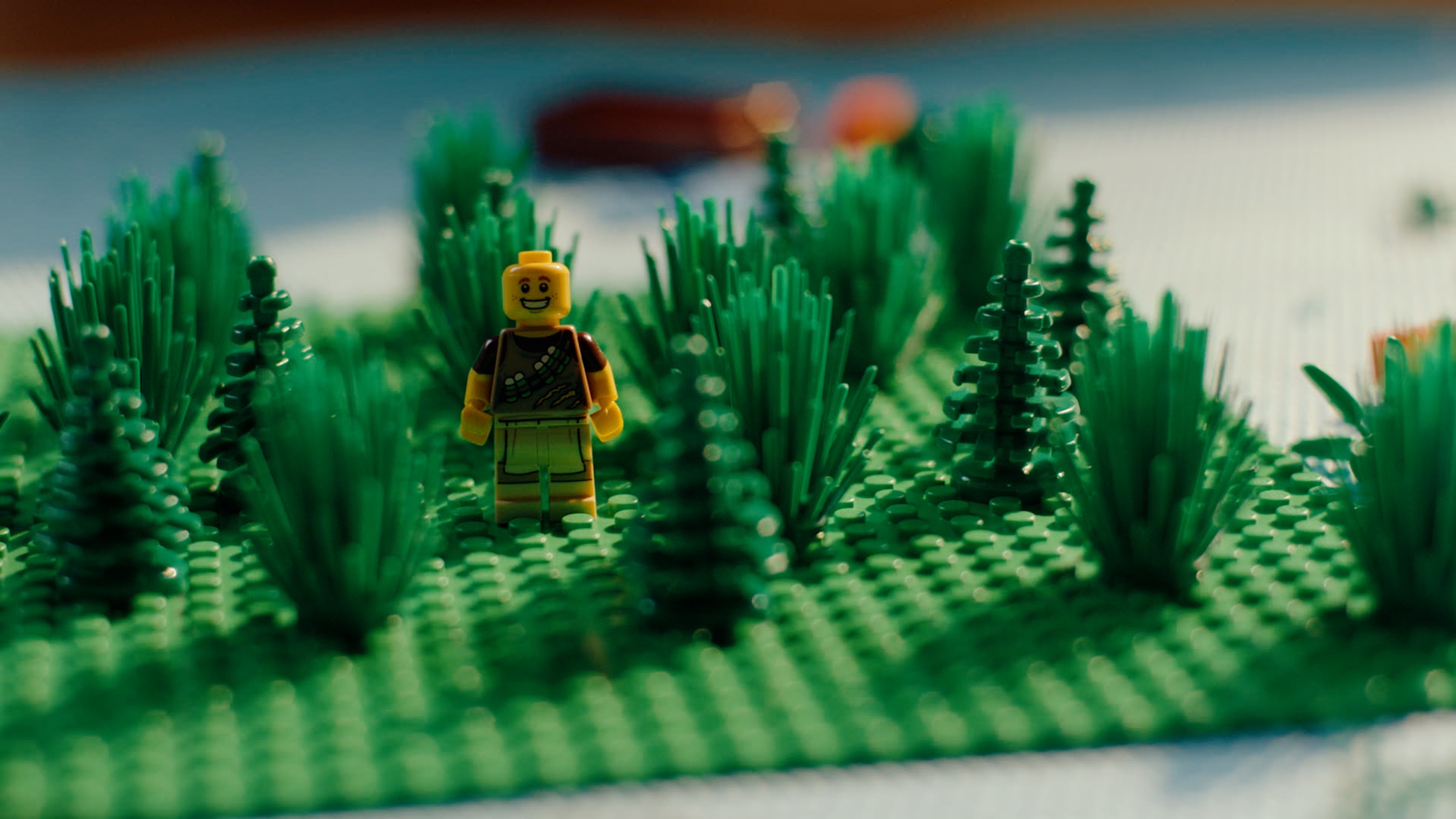A LEGO minifigure standing in a forest built from green LEGO bricks